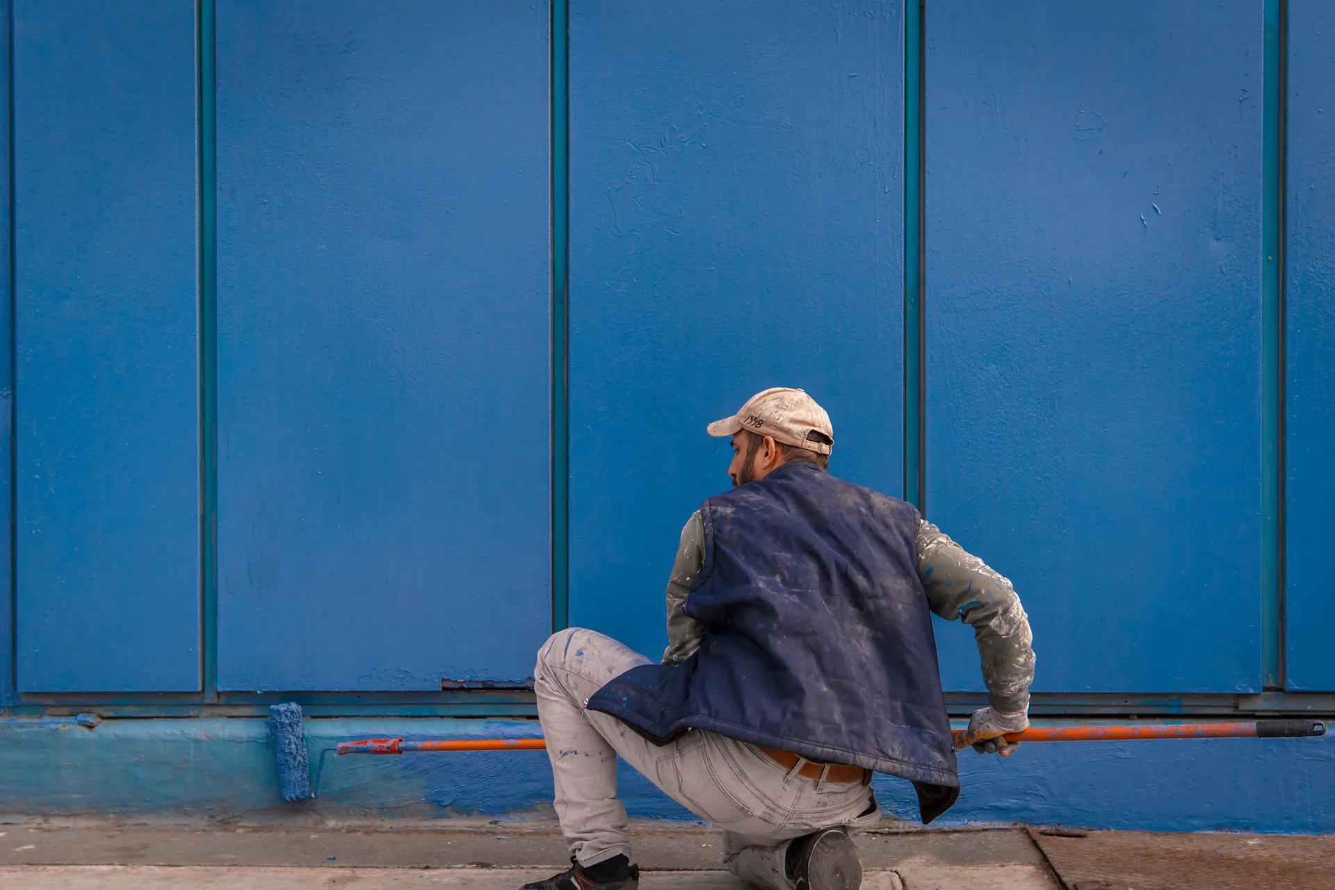 Painter carefully rolling a blue exterior wall, representative of NM Painting's work in Topeka, KS